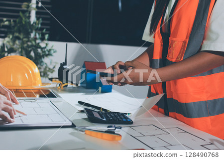 Closeup of team of industrial engineers meeting analyze machinery blueprints consult project on table in manufacturing factory. Working in manufacturing plant or production plant. 128490768