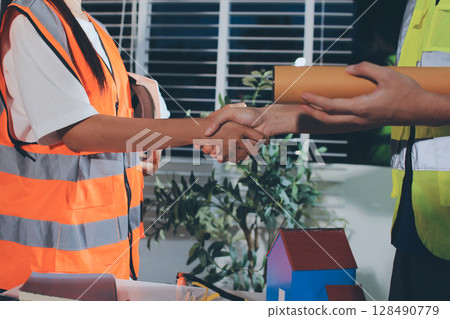 Closeup of team of industrial engineers meeting analyze machinery blueprints consult project on table in manufacturing factory. Working in manufacturing plant or production plant. 128490779