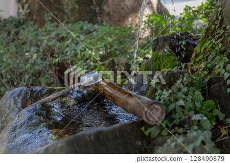 [Japan] Water flowing into a bamboo tube and ladle at the chozuya (purification fountain) at Matsudo Shrine in Chiba Prefecture 128490879