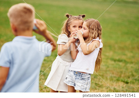 Talking, using string can toy. Kids are having fun on the field at daytime together 128491541
