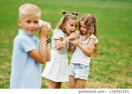 Talking, using string can toy. Kids are having fun on the field at daytime together 128491543