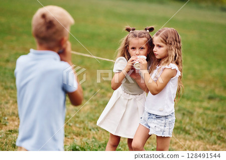 Talking, using string can toy. Kids are having fun on the field at daytime together Talking, using string can toy. Kids are having fun on the field at daytime together 128491544