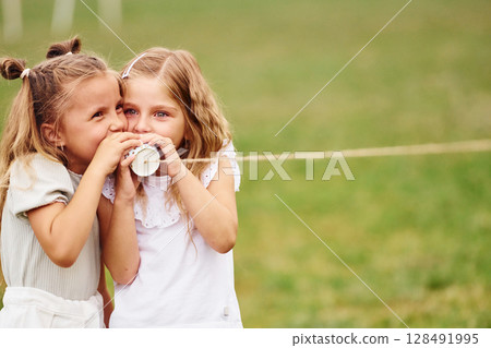String can toy. Two girls are playing together on the green field String can toy. Two girls are playing together on the green field 128491995