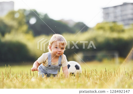 Cute little boy is on the field with soccer ball, at daytime 128492147