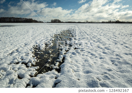 A frozen puddle in a snow-covered field 128492167