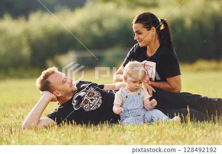 Family of mother, father and little boy is on thee green field with soccer ball 128492192
