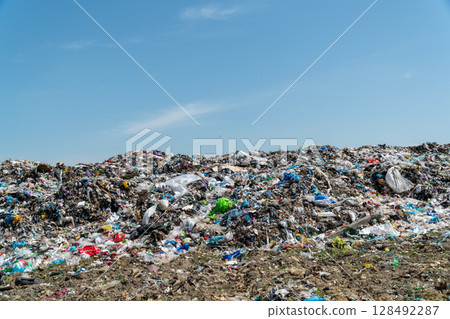 A large landfill filled with various types of waste under a clear blue sky shows the pressing need for effective waste management practices A large landfill filled with various types of waste under a clear blue sky shows the pressing need for effective waste management practices 128492287