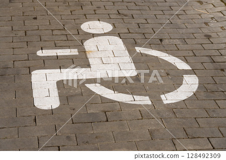 A clear wheelchair access symbol is prominently painted on the pavement in an urban setting, emphasizing the importance of accessibility for all A clear wheelchair access symbol is prominently painted on the pavement in an urban setting, emphasizing the importance of accessibility for all 128492309