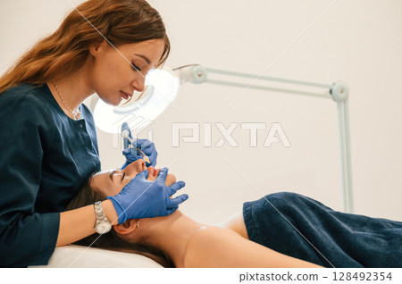 Cosmetologist does injection for lips augmentation. Women's cosmetology in the beauty salon Cosmetologist does injection for lips augmentation. Women's cosmetology in the beauty salon 128492354