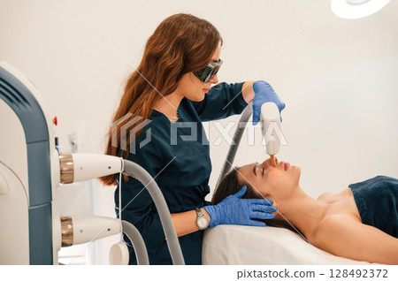 Lying down. Getting photo rejuvenation procedure at cosmetology clinic 128492372