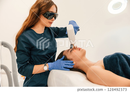 Lying down. Getting photo rejuvenation procedure at cosmetology clinic 128492373