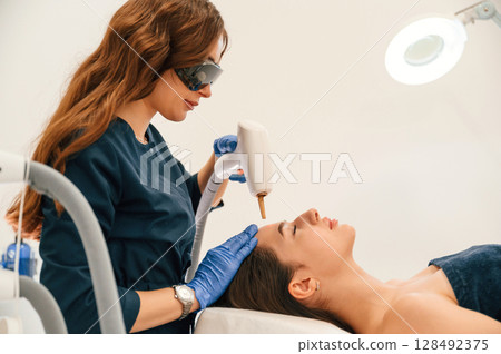Getting photo rejuvenation procedure at cosmetology clinic. Woman is getting LPG hardware massage in beauty salon Getting photo rejuvenation procedure at cosmetology clinic. Woman is getting LPG hardware massage in beauty salon 128492375