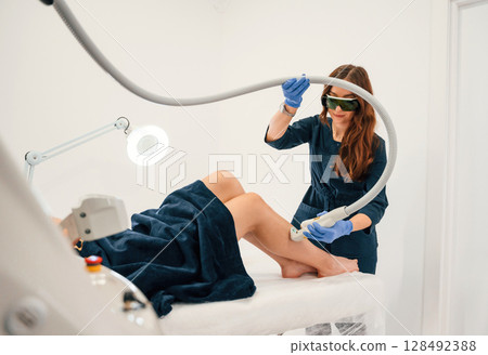 Procedure on the legs. Getting photo rejuvenation at cosmetology clinic. Women in beauty salon Procedure on the legs. Getting photo rejuvenation at cosmetology clinic. Women in beauty salon 128492388
