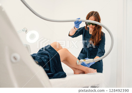 Procedure on the legs. Getting photo rejuvenation at cosmetology clinic. Women in beauty salon Procedure on the legs. Getting photo rejuvenation at cosmetology clinic. Women in beauty salon 128492390