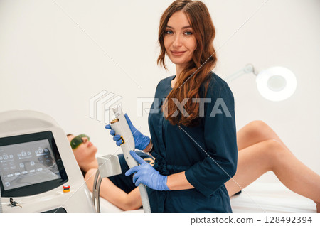 Modern device. Getting photo rejuvenation procedure at cosmetology clinic. Women in beauty salon Modern device. Getting photo rejuvenation procedure at cosmetology clinic. Women in beauty salon 128492394