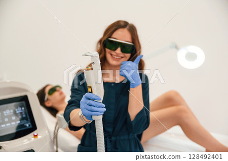 Holding device. Getting photo rejuvenation procedure at cosmetology clinic. Women in beauty salon 128492401