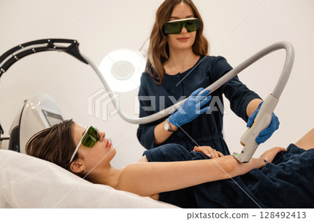 Procedure on the hands. Getting photo rejuvenation at cosmetology clinic. Women in beauty salon Procedure on the hands. Getting photo rejuvenation at cosmetology clinic. Women in beauty salon 128492413