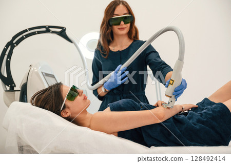 Procedure on the hands. Getting photo rejuvenation at cosmetology clinic. Women in beauty salon Procedure on the hands. Getting photo rejuvenation at cosmetology clinic. Women in beauty salon 128492414