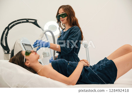 Professional occupation. Getting photo rejuvenation procedure at cosmetology clinic. Women in beauty salon 128492418