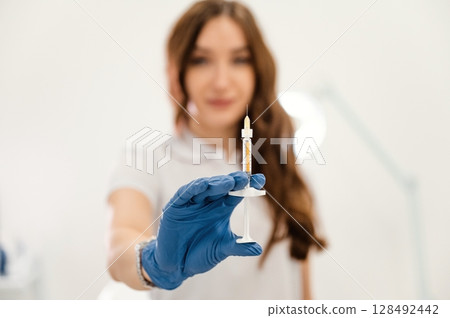 Close up view. Cosmetologist holding syringe for injection lips augmentation. Women's cosmetology in the beauty salon 128492442