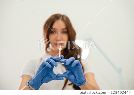 Close up view. Cosmetologist holding syringe for injection lips augmentation. Women's cosmetology in the beauty salon 128492444