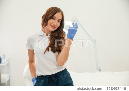 Cosmetologist holding syringe for injection lips augmentation. Women's cosmetology in the beauty salon Cosmetologist holding syringe for injection lips augmentation. Women's cosmetology in the beauty salon 128492446