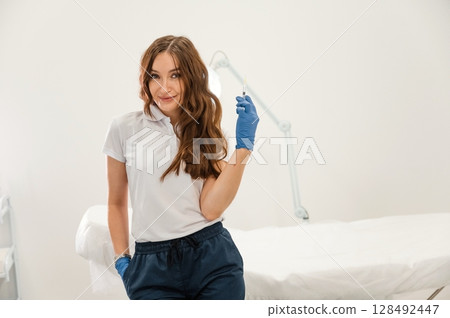 Cosmetologist holding syringe for injection lips augmentation. Women's cosmetology in the beauty salon 128492447