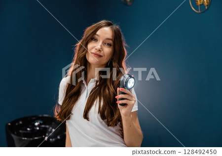 Woman cosmetologist is holding device with light Woman cosmetologist is holding device with light 128492450