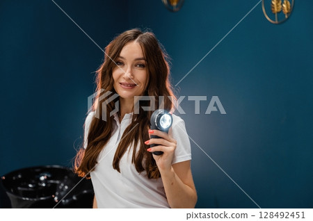 Woman cosmetologist is holding device with light Woman cosmetologist is holding device with light 128492451