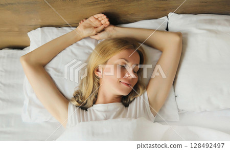 Woman sleeping lying in bed on white soft comfortable pillow in bedroom at home 128492497
