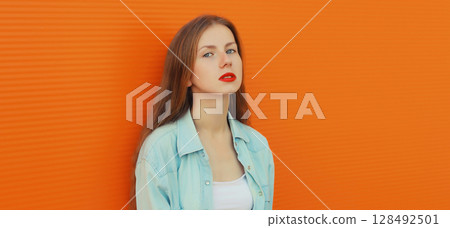 Portrait of modern teenage girl, young female model in casual clothing posing on orange background Portrait of modern teenage girl, young female model in casual clothing posing on orange background 128492501