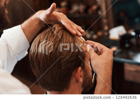 Getting haircut. Man is visiting modern barber shop. Modern style Getting haircut. Man is visiting modern barber shop. Modern style 128492636