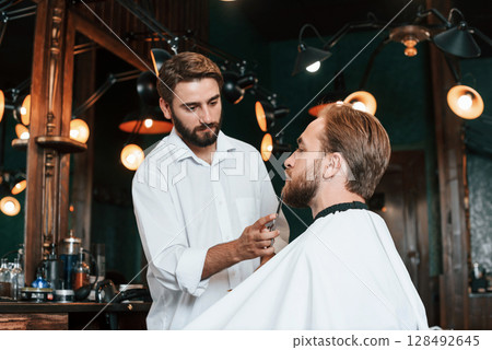 Using scissors. Man is visiting modern barber shop. Modern style Using scissors. Man is visiting modern barber shop. Modern style 128492645