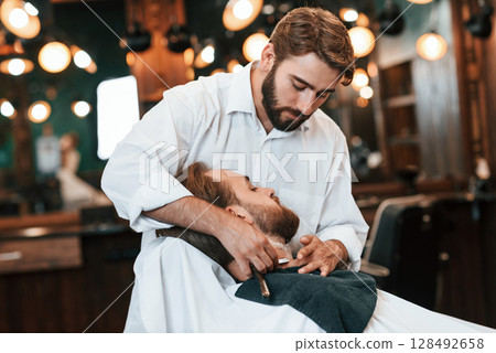 Sitting on the chair. Man is visiting modern barber shop. Modern style 128492658