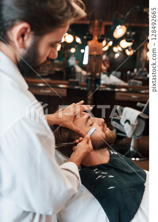 Sitting on the chair. Man is visiting modern barber shop. Modern style Sitting on the chair. Man is visiting modern barber shop. Modern style 128492665
