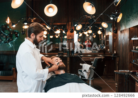 Sitting on the chair. Man is visiting modern barber shop. Modern style 128492666