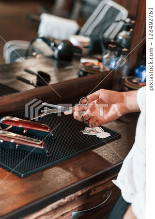 Close up view of barber hand that is holding scissors Close up view of barber hand that is holding scissors 128492761