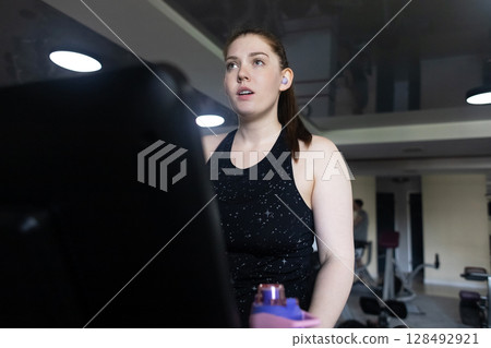 Real woman with a normal body working out on treadmill in gym. Realistic fitness and healthy weight loss motivation Real woman with a normal body working out on treadmill in gym. Realistic fitness and healthy weight loss motivation 128492921