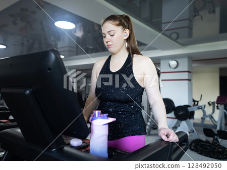 Real woman with a normal body working out on treadmill in gym. Realistic fitness and healthy weight loss motivation Real woman with a normal body working out on treadmill in gym. Realistic fitness and healthy weight loss motivation 128492950