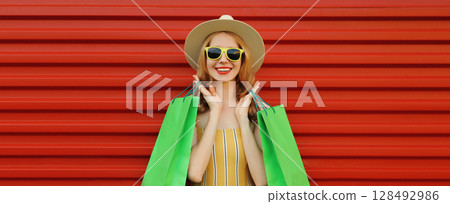 Shopping day! Stylish beautiful happy smiling young woman with green shopping bags, wear summer hat 128492986