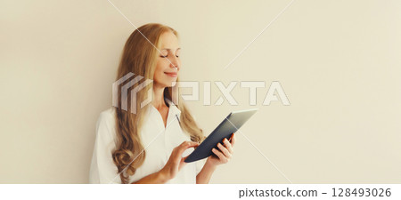Happy smiling young woman employee with digital tablet computer or folder with documents in office Happy smiling young woman employee with digital tablet computer or folder with documents in office 128493026