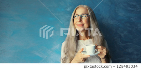 Happy smiling woman enjoying hot tasty cup of coffee or tea standing in morning at home Happy smiling woman enjoying hot tasty cup of coffee or tea standing in morning at home 128493034