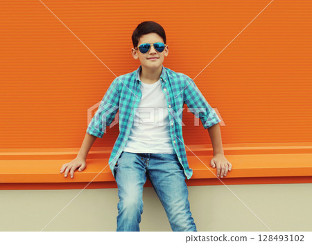 Modern teenage kid boy in casual clothes with glasses standing on city street 128493102