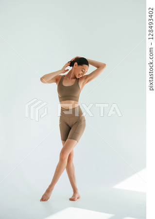 Khaki clothes. Young woman with slim body type is in the studio 128493402