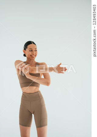 Smiling, feeling good. Young woman with slim body type is in fitness clothes in the studio Smiling, feeling good. Young woman with slim body type is in fitness clothes in the studio 128493403