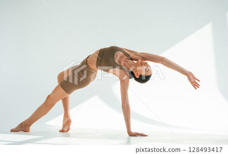 Flexibility of human body. Young woman is in fitness clothes in the studio Flexibility of human body. Young woman is in fitness clothes in the studio 128493417