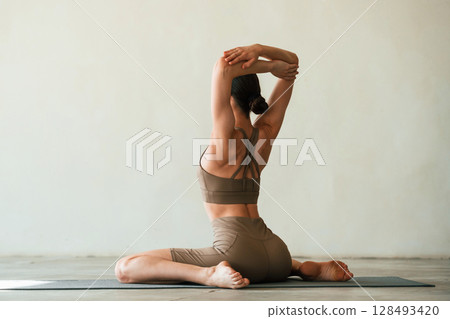 In grey fitness clothes. Young woman with slim body type is in the studio 128493420
