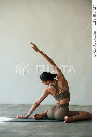 In grey fitness clothes. Young woman with slim body type is in the studio In grey fitness clothes. Young woman with slim body type is in the studio 128493424