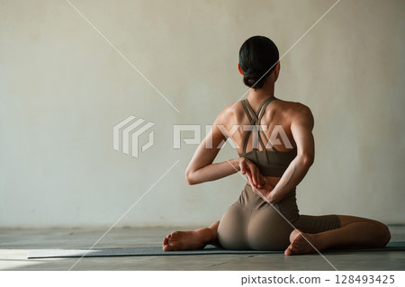 Yoga session. Young woman with slim body type is in fitness clothes in the studio 128493425