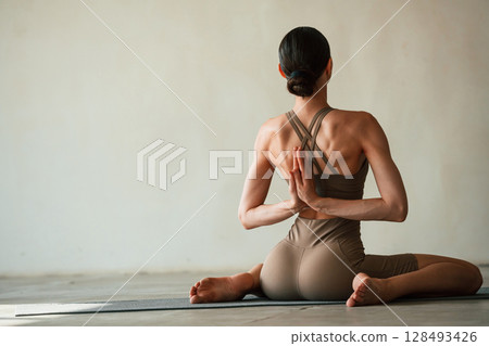 Yoga session. Young woman with slim body type is in fitness clothes in the studio Yoga session. Young woman with slim body type is in fitness clothes in the studio 128493426